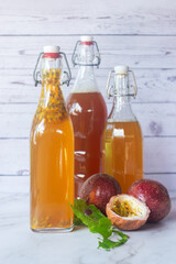 Kombucha second fermentation with passion fruit flavor in swing top bottles on white table background.