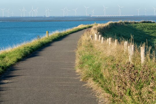 path on the dike, wind turbines in the background