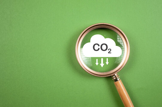 Hand holding CO2 reducing icon inside magnifier glass for focusing decrease CO2 or carbon dioxide emission ,carbon footprint and carbon credit to limit global warming from climate change concept..