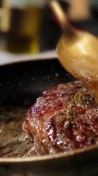Close-up of a juicy steak roasting in a hot pan inside a restaurant kitchen