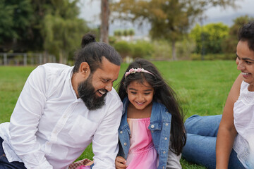 Happy indian parents having playful time with little daughter at city park - Hindu family love and culture concept