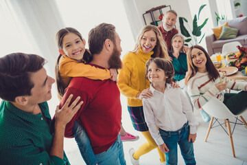 Photo of big family have fun playing together piggyback celebrate holiday dinner multi-generation relatives living room weekend