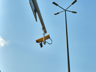 CCTV camera on a street light pole with blue sky background.