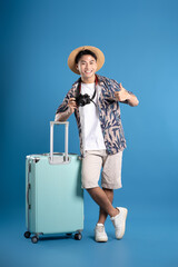Full body image of Asian guy using camera to travel and posing on blue background