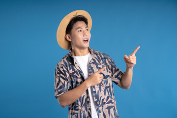 Portrait of Asian man wearing summer clothes posing on blue background
