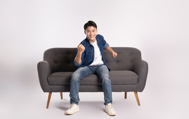 Full body image of young Asian man posing on sofa on white background