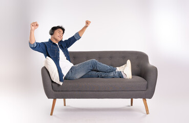 Full body image of young Asian man posing on sofa on white background