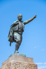 The statue of Vojvoda Vuk stands prominently in Belgrade, Serbia, depicting the historical figure pointing skyward, surrounded by a bright blue sky.