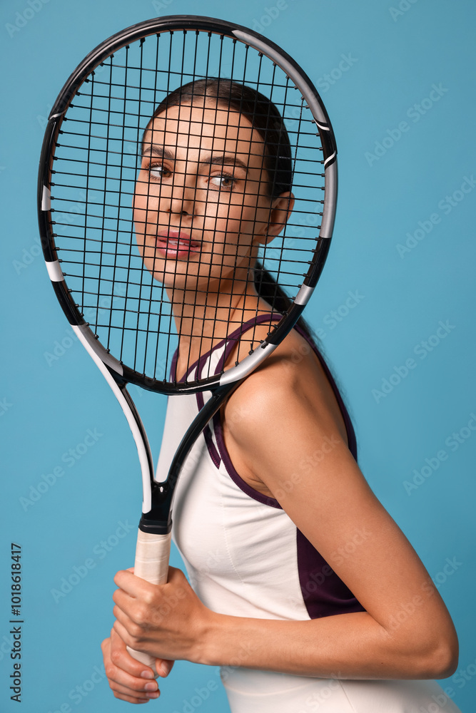 Wall mural Beautiful young woman with tennis racket on light blue background