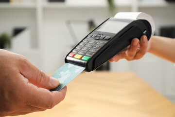 Customer making payment by putting credit card into POS machine indoors, closeup