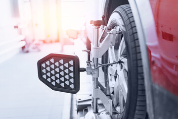 Closeup car wheel alignment on stand with sensors check in service station. Vehicle inside garage...