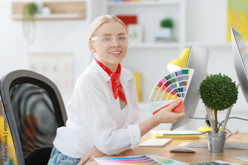 Poster designer with color samples working at table in office