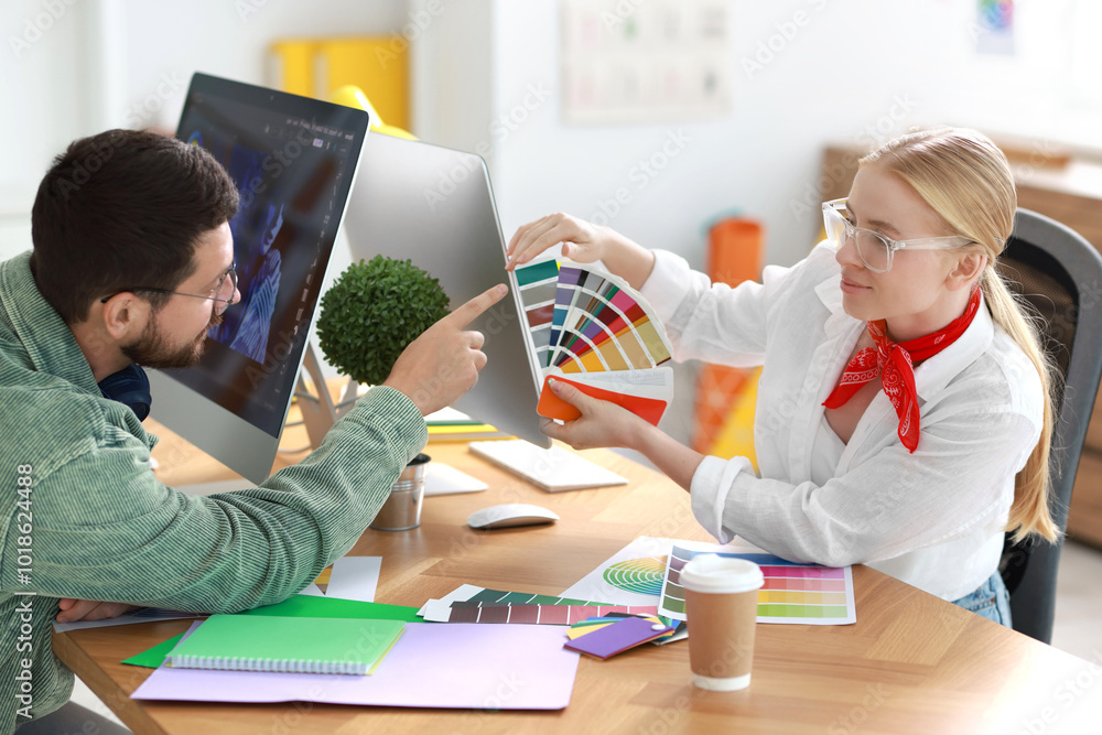 Poster designers with color samples working together at table in office