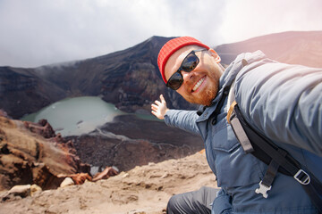 Trip adventure tour Kamchatka, Russia. Tourist man takes selfie photo against backdrop of Gorely volcano