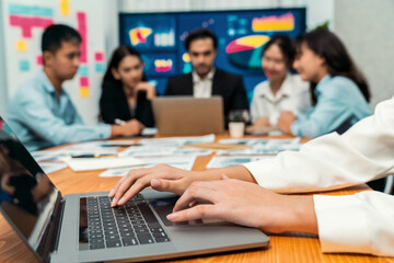 Fototapeta premium Closeup hand typing keyboard laptop with blurred background of business people using laptop to analyze financial data or data analysis display on screen background. Meticulous