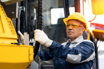 Adult man worker checks piping system of hydraulic hose valves in industrial equipment