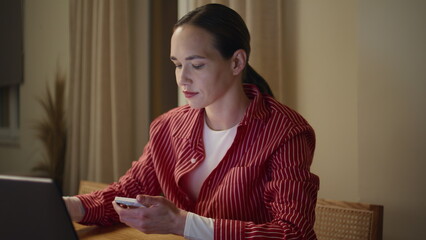 Woman multitasking laptop smartphone in late home office. Closeup freelancer sip