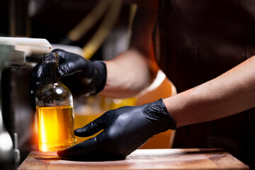 Worker hold bottle with yellow extra virgin oil of sunflower on production, eco healthy food manufacturing