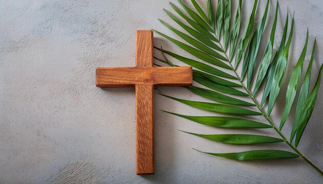 Wooden Cross and green palm leaf on cement background. Religion and Christian fait concept.