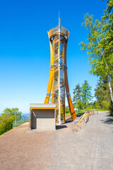 The Hamstejn lookout tower stands tall with a spiral staircase and steel structure, blending architecture and nature. Visitors can enjoy panoramic views of the picturesque Bohemian Paradise.