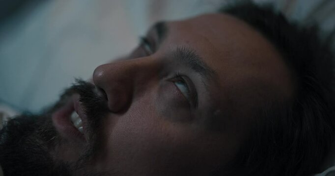 Patient lying in bed, eyes closing tightly as if experiencing epileptic seizures.