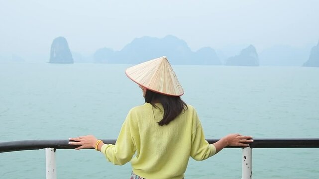 Woman tourist traveler stand on cruise boat in Halong Bay national park in Vietnam consisting of thousands of small and big limestone islands. Travel to Vietnam concept. Excited hands up spreaded