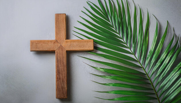 Wooden Cross and green palm leaf on cement background. Religion and Christian fait concept.