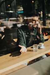 Toughtful man savoring coffee alone at a cozy cafe on a sunny day while lost in contemplation by the window