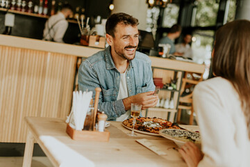 A joyful couple enjoying a delightful meal together at a cozy restaurant during a sunny afternoon