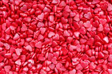 Background of little red and pink hearts.Close-up mini hearts candy.Varied sugar sprinkles, stars, flowers,hearts, dots.Toppings for desserts and ice cream.