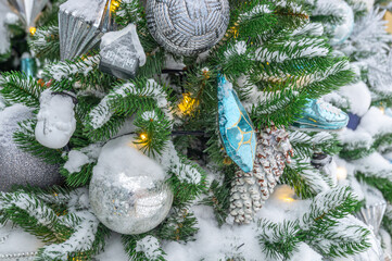 Christmas decorations on a snow-covered Christmas tree. Background of Christmas tree toys. Festive...