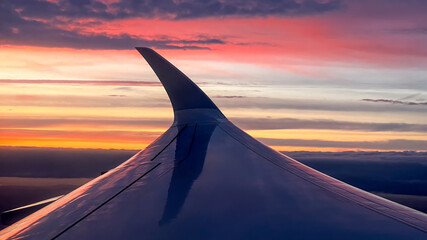 Airplane wing against a vibrant sunset sky, capturing the essence of travel and adventure during a...