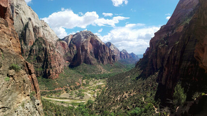 Majestic panoramic view of Zion National Park's rugged cliffs and green valleys under a clear blue sky, ideal for adventure travel inspirations