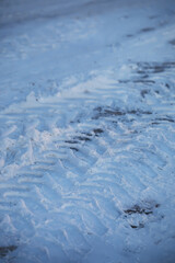 Fototapeta premium Snowy Terrain with Tire Tracks and Ice in Winter Landscape