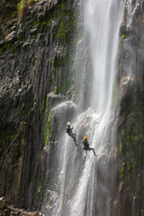 Dos personas bajando con cuerdas por una cascada