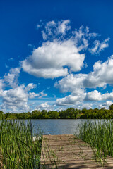 Carp fishing, wooden platform on the lake.Carp Angling scenic landscape overlooking lake at and blue sky with clouds.Fishing adventures.