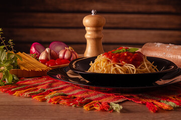 Sao Paulo, SP, Brazil - August 16 2022: Delicious spaghetti served on a black plate with ingredients in the background details.