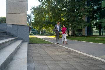 Business people, walking and travel in city with discussion on morning commute, partnership and happy. Employees, man and woman with conversation, collaboration and networking outdoor in urban town