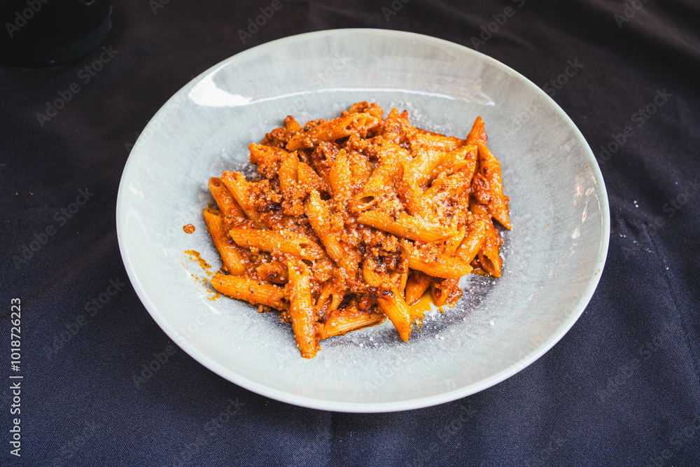 Wall mural side view of a plate of penne pasta with rich bolognese sauce served on a plain grey plate. perfect 