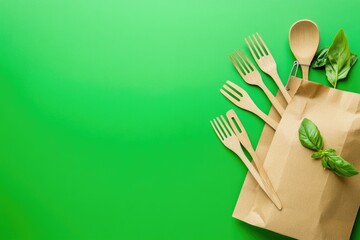 A brown paper bag with utensils on a green surface, ideal for outdoor or picnic scenes