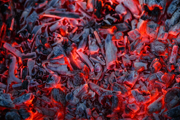 Background of burning and glowing hot coals.Flicker of burning coals at night.The texture of...