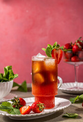 Refreshing iced tea with strawberries and mint on a pink background