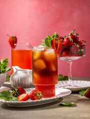Iced tea with strawberries and mint on a pink background