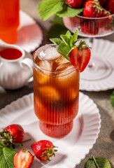 Strawberry iced tea decorated with fresh mint and strawberries on a table