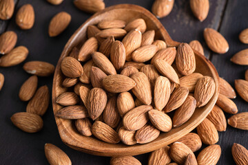 Almonds in a heart shaped wooden bowl, healthy vegan snack food