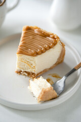 Cheesecake slice with caramel sauce topping missing a bite