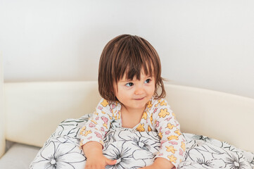 Fototapeta premium Pillow fight time, a little baby girl loves playing with her pillow 