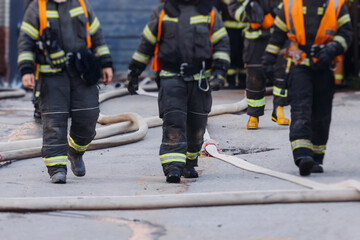 Group of fire men in uniform during fire fighting operation in the city streets, firefighters with the fire engine truck vehicle in the background, emergency and rescue, fire drill, exercise training