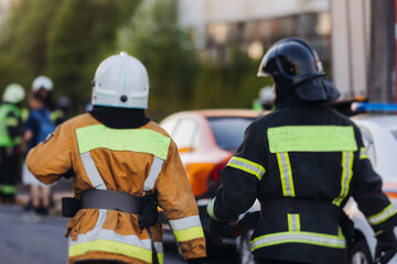 Group of fire men in uniform during fire fighting operation in the city streets, firefighters with...