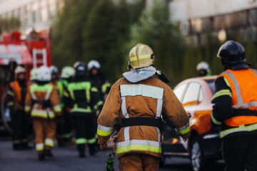 Group of fire men in uniform during fire fighting operation in the city streets, firefighters with the fire engine truck vehicle in the background, emergency and rescue, fire drill, exercise training